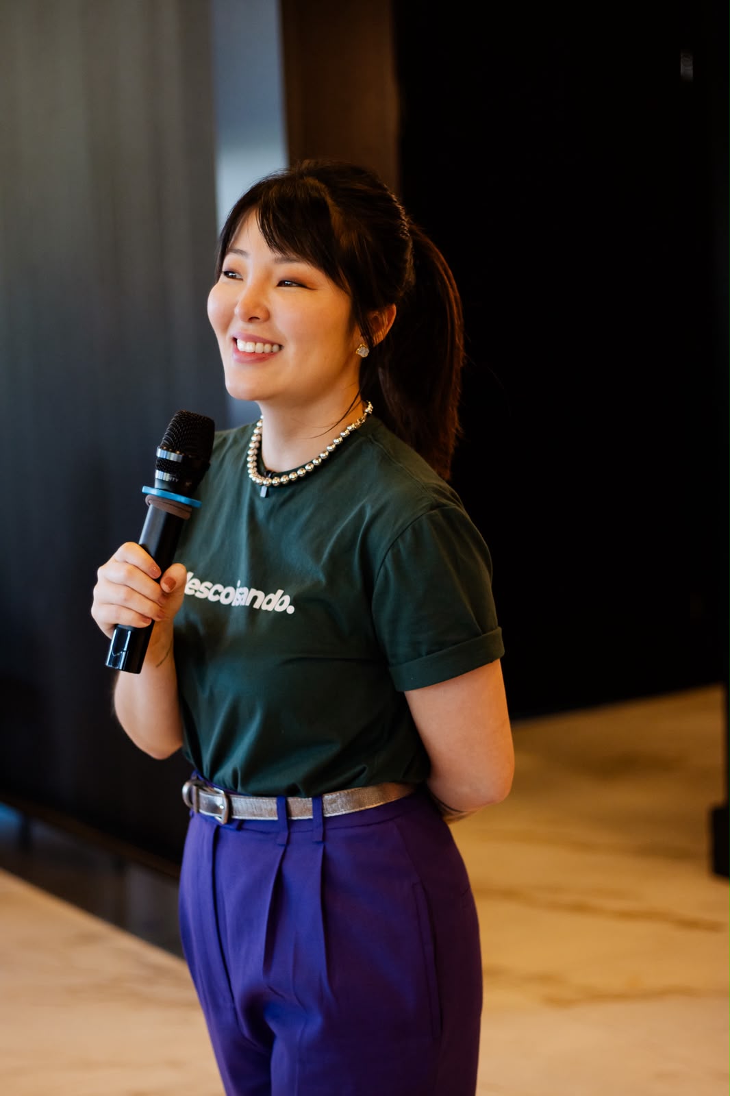 Erika Yumi sorrindo com um microfone